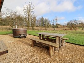 An outdoor area with a wooden hot tub and a table with benches at Harriet in Llangurig