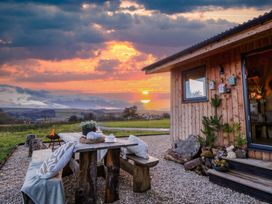 An outdoor area with a wooden table and fire pit at Harriet in Llangurig