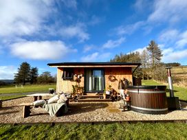 A cabin with a hot tub and chairs on the deck at Harriet in Llangurig