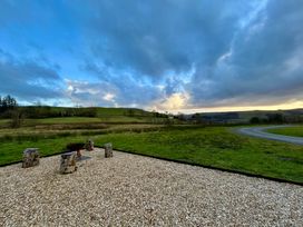 An outdoor area with a fire pit surrounded by wooden logs at Harriet in Llangurig