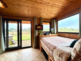 A bedroom with a bed and windows looking out at the countryside at Harriet in Llangurig