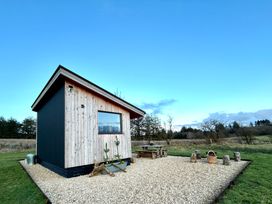 A wooden cabin with outdoor seating and planters at Harriet in Llangurig