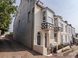 An exterior view of a building with balconies and a sidewalk at Garden Studio at Stanley House Charmouth
