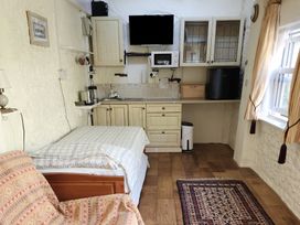 A studio with bed, kitchenette and television at Garden Studio at Stanley House Charmouth