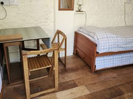 A bedroom with a bed, table and chair at Garden Studio at Stanley House in Charmouth