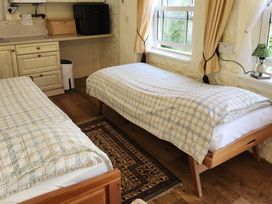 A bedroom with two single beds and kitchenette at Garden Studio at Stanley House in Charmouth