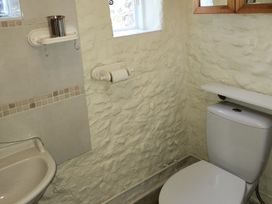 A bathroom with a sink, toilet, and shelf at Garden Studio at Stanley House in Charmouth