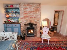 A living room with a stove and a bookshelf at The Hare & the Bumblebee Cottage