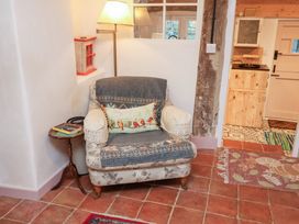 A living room with an armchair and a side table at The Hare & the Bumblebee Cottage