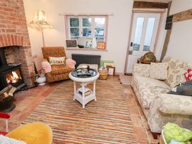 A living room with a fireplace and seating at The Hare & the Bumblebee Cottage