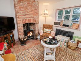 A living room with a fireplace and armchair at The Hare & the Bumblebee Cottage