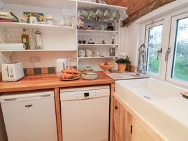 A kitchen with a sink, dishwasher, and countertop with food items at The Hare & the Bumblebee Cottage