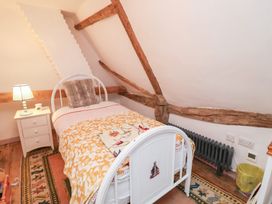 A bedroom with a bed, nightstand, and lamp at The Hare & the Bumblebee Cottage 