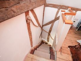 A staircase with wooden handrail and wall details at The Hare & the Bumblebee Cottage 