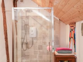 A shower area with tiles and towels at The Hare & the Bumblebee Cottage