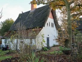 An outdoor view of a cottage with a thatched roof and garden at The Hare & the Bumblebee Cottage 