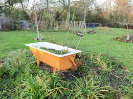A garden with a bathtub planter and various plants at The Hare & the Bumblebee Cottage