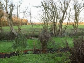 A garden with trees and grass at The Hare & the Bumblebee Cottage 
