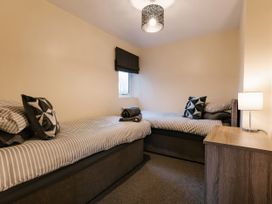A bedroom with two single beds and a lamp at Raven Lodge in Brigg