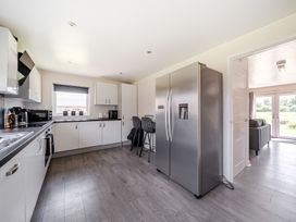 A kitchen with a refrigerator, sink, and bar stools at Raven Lodge Near Brigg