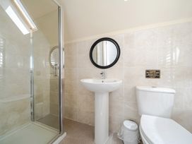 A bathroom with a shower, sink, toilet, and mirror at Raven Lodge Near Brigg