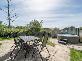 An outdoor area with a table, chairs and a hot tub at Raven Lodge Near Brigg
