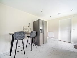 A kitchen with a refrigerator and bar stools at Charcoal Lodge in Brigg