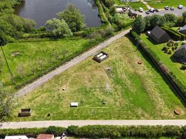 An outdoor area with grass, trees, playground equipment, and a water body at Charcoal Lodge in Brigg