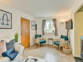 A living room with armchairs and a TV at The Old Boat House in Lyme Regis