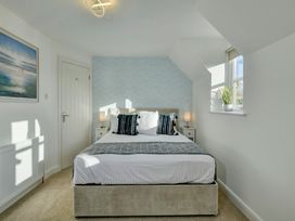 A bedroom with a bed, bedside tables and windows at The Old Boat House in Lyme Regis