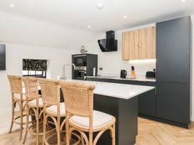 A kitchen with bar stools and modern appliances at The Old Bakehouse