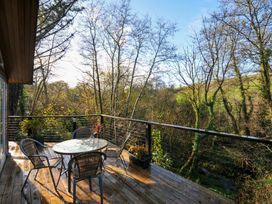 A terrace with a table and chairs overlooking trees at 6 Stonerush Valley Looe