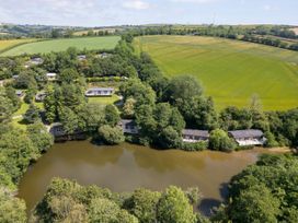A view of houses near a pond surrounded by trees and fields at 6 Stonerush Valley in Lanreath