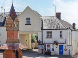 A clock tower and buildings with flowers at The Old Bank Flat in North Tawton
