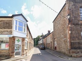 A street with a pharmacy and brick buildings at The Old Bank Flat in North Tawton
