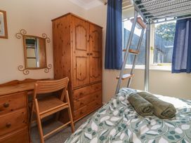 A bedroom with a bed, wardrobe, desk, and a ladder at Stargazy, Falmouth
