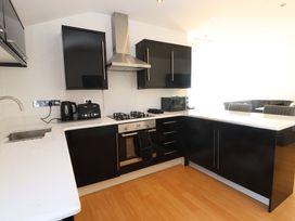 A kitchen with cabinets, sink, kettle, toaster, microwave, gas stove at 1 Marina View, Pwllheli