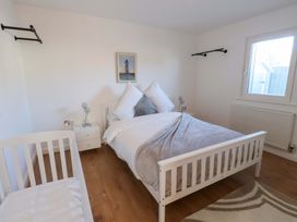 A bedroom with a bed and crib at 1 Marina View Pwllheli
