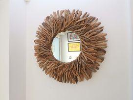 A circular driftwood mirror on the wall at 1 Marina View in Pwllheli
