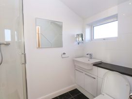 A bathroom with a shower, sink, toilet, and a mirror at 1 Marina View Pwllheli