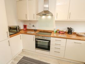 A kitchen with a microwave, oven, kettle, and kitchen cabinets at Harbour View Poole