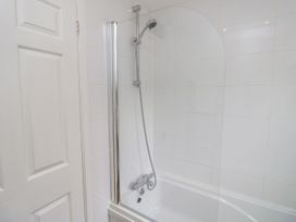 A bathtub with shower and wall tiles at Harbour View Poole