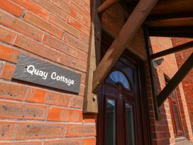A nameplate on a brick wall identifying Quay Cottage in Poole