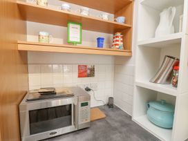 A kitchen with a microwave and mugs on a shelf at Poole Quay Cottage in Poole