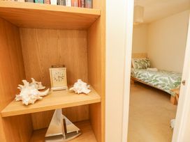 A bookshelf with decor and view of bed at Poole Quay Cottage in Poole