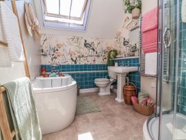 A bathroom with a bathtub, toilet, and sink at Captains Barn in Tiverton