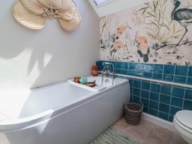 A bathroom with a bathtub and colorful tiles at Captains Barn Tiverton