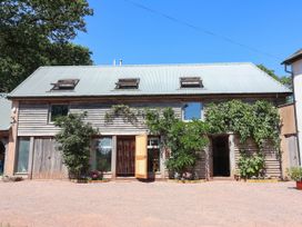 A wooden building with windows and plants at Captains Barn Tiverton