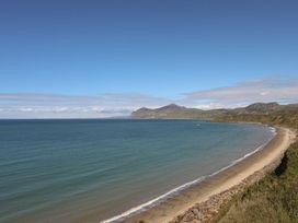 A beach shoreline with mountains in the background at Bodefi in Pwllheli