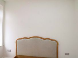 A bedroom with a headboard against a wall at Beachwalk Villa 2 in Whitby